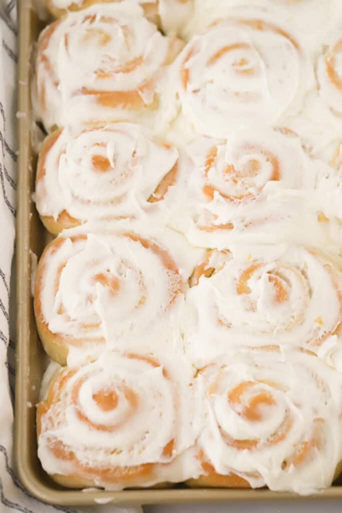 lemon sweet rolls in a baking sheet covered in lemon buttercream frosting.