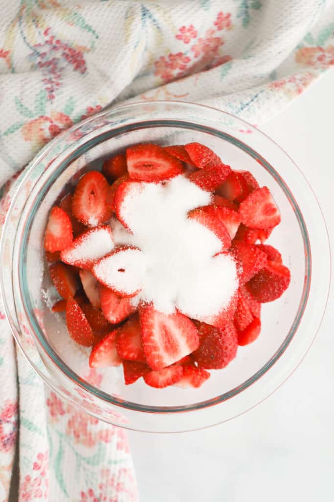 Macerated Strawberries being made in a glass bowl.