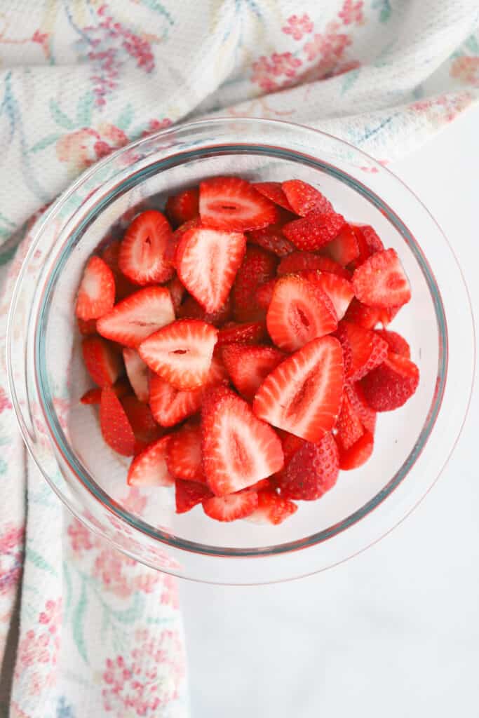 A bowl of sliced strawberries in a glass bowl.