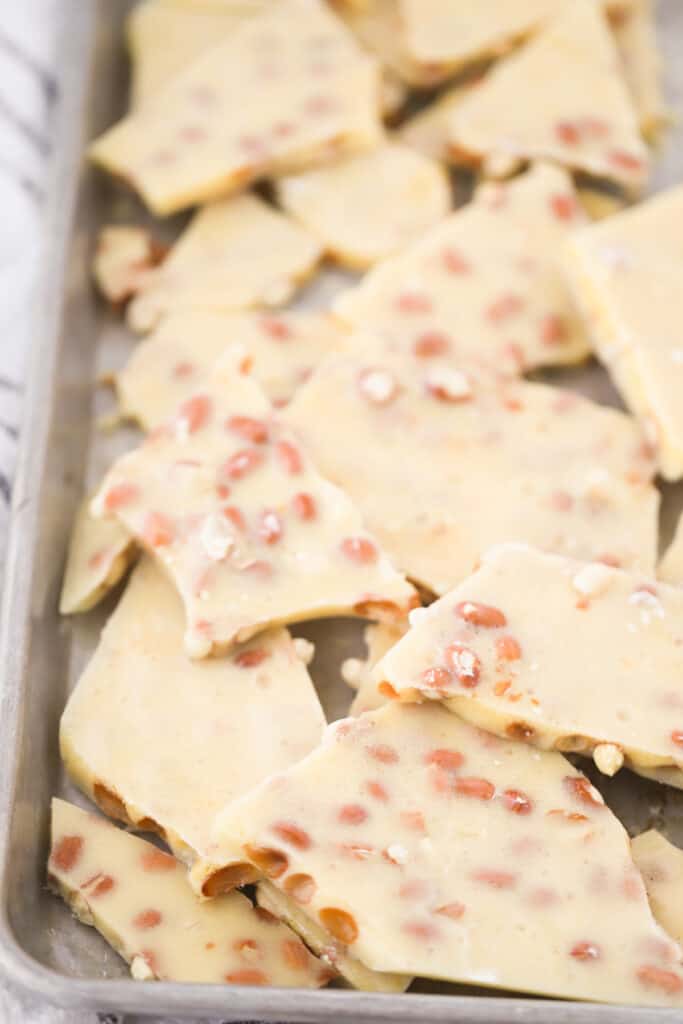 An old-fashioned peanut brittle recipe broken into pieces and laying on a baking sheet.