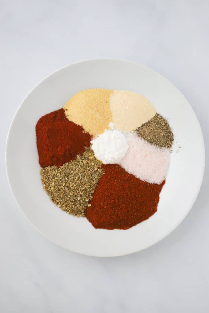 Different spices in a white bowl ready to make a spice mix.
