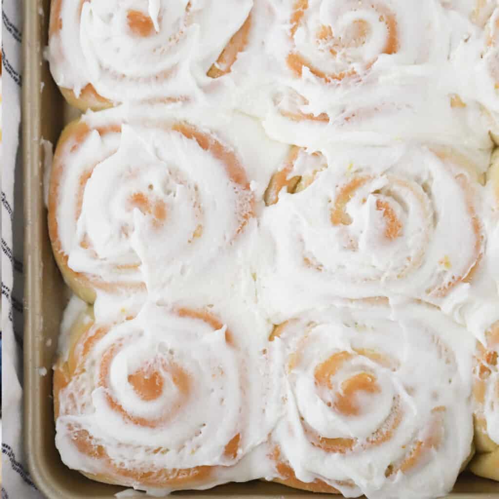 A sheet tray full of lemon sweet rolls topped with frosting.