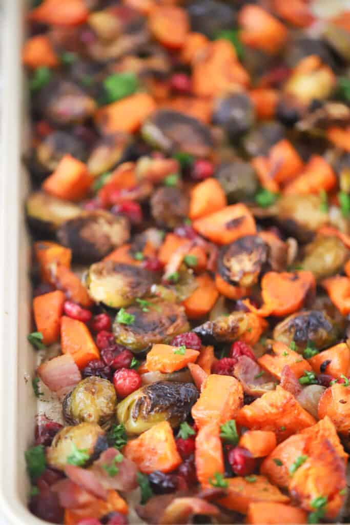 A sheet tray filled with roasted sweet potatoes, brussels sprouts cranberries and onions.
