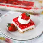 a square piece of strawberry salad recipe with whipped cream and a strawberry.