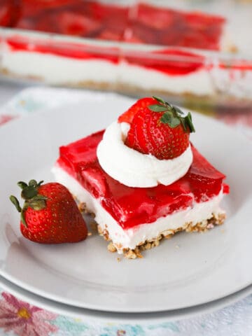 a square piece of strawberry salad recipe with whipped cream and a strawberry.