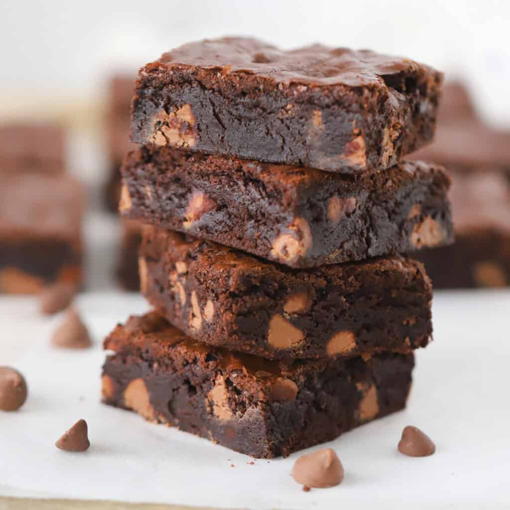 A stack of fudge brownies full of chocolate chips.