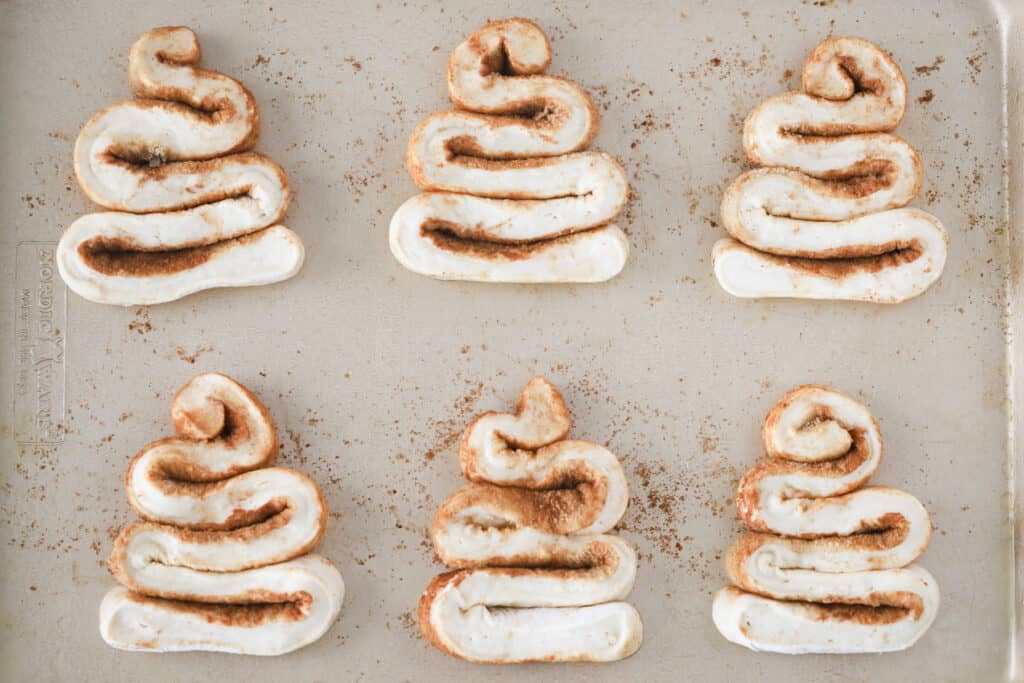 A sheet pan with rows of Christmas Tree Cinnamon Rolls ready to bake in the oven. cinnamon roll Christmas tree. 