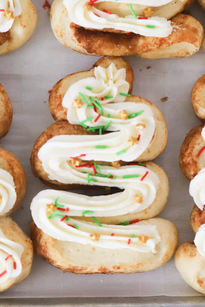Cinnamon rolls shaped like christmas trees on a sheet tray, decorated with frosting and sprinkles. Christmas morning cinnamon rolls, cinnamon rolls Christmas, 