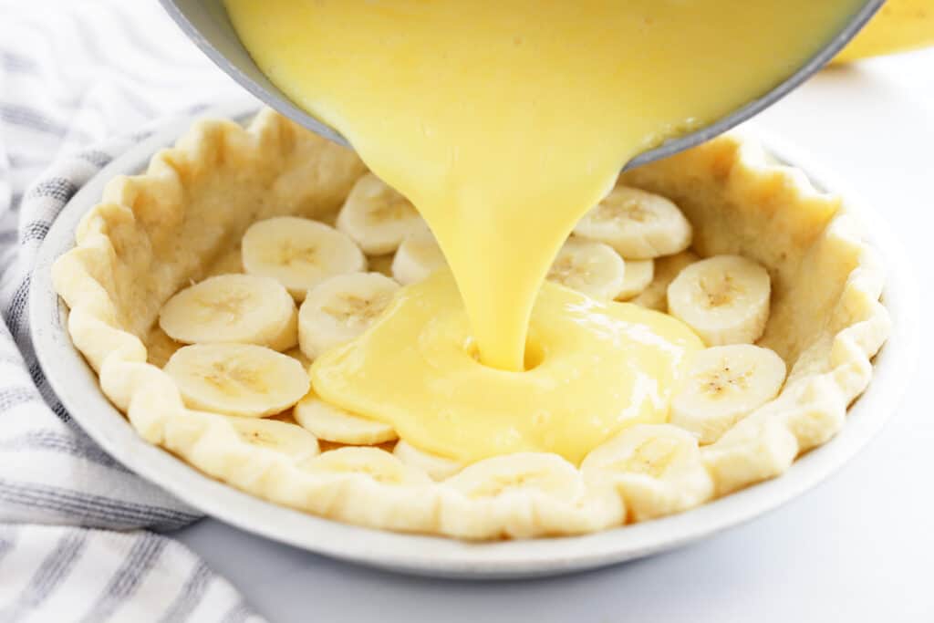 pouring the best banana cream filling Recipe into a prepared pie crust, best banana cream pie recipe, banana tart.