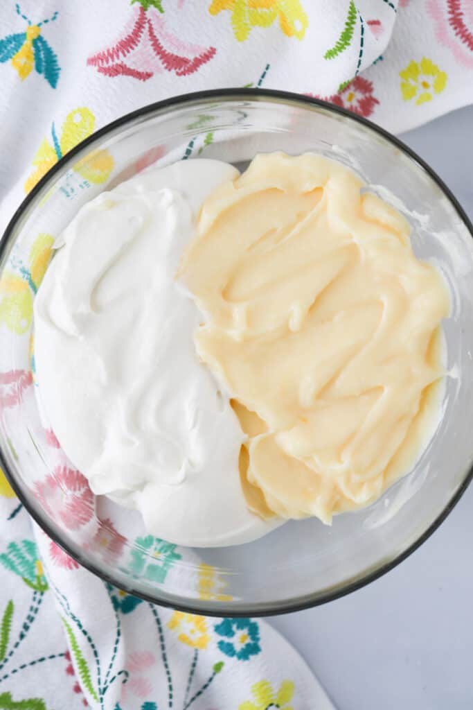 A glass bowl filled with half pastry cream and half whipped cream, about to mix together to make the Custard Cream Puffs filling. vanilla custard filling recipe, custard recipe for cream puffs.