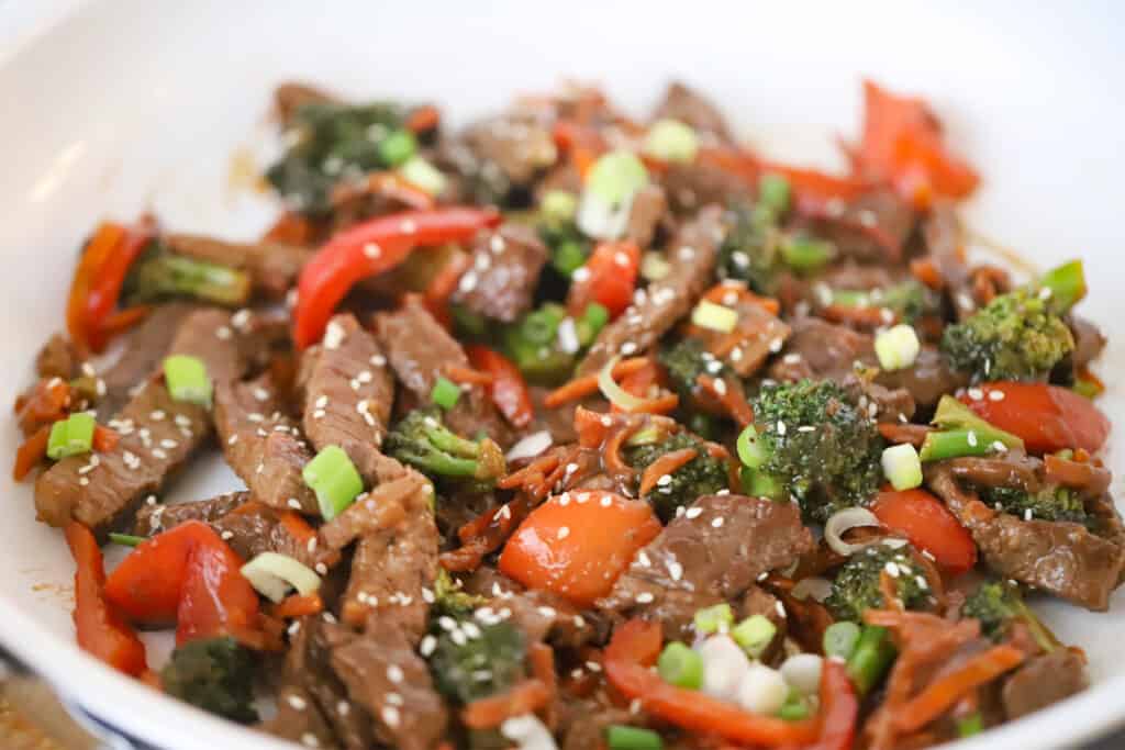 Korean Beef Stir Fry in a skillet topped with sliced green onions and sesame seeds. Stir fry Korean.