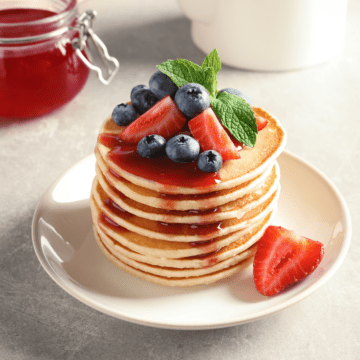Pancakes with strawberry syrups on a stack of pancakes