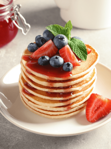 Pancakes with strawberry syrups on a stack of pancakes