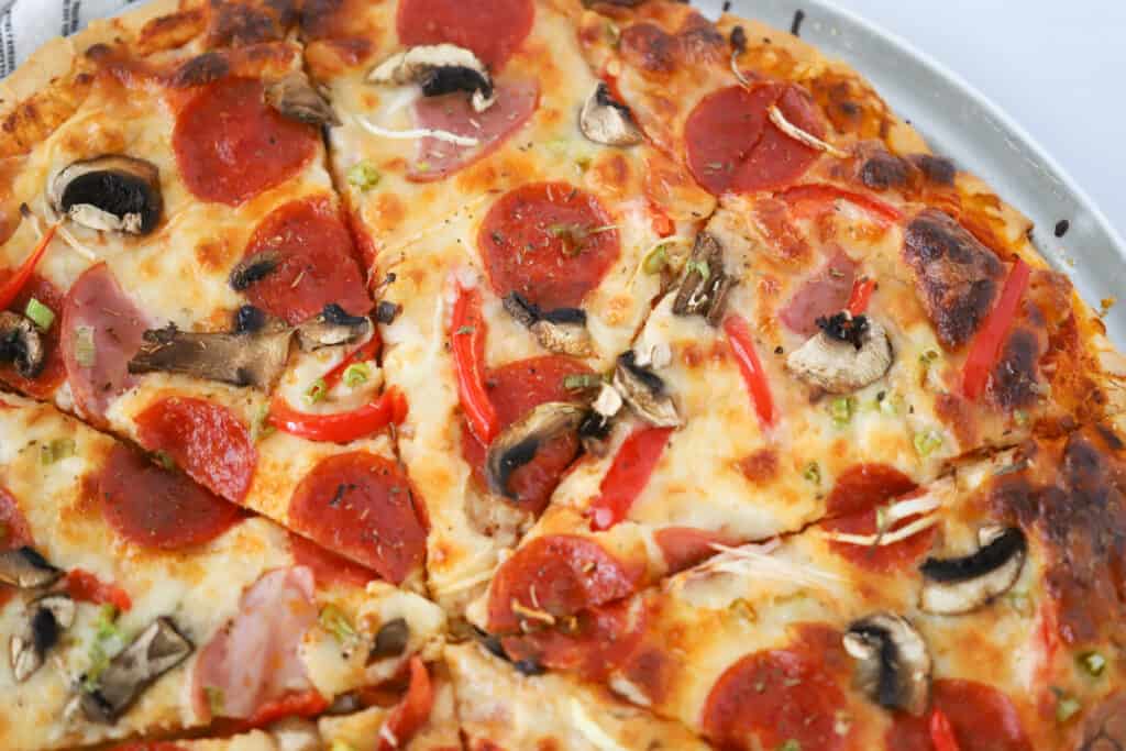 A sliced Combination Pizza topped with pepperoni, mushrooms, peppers and more.