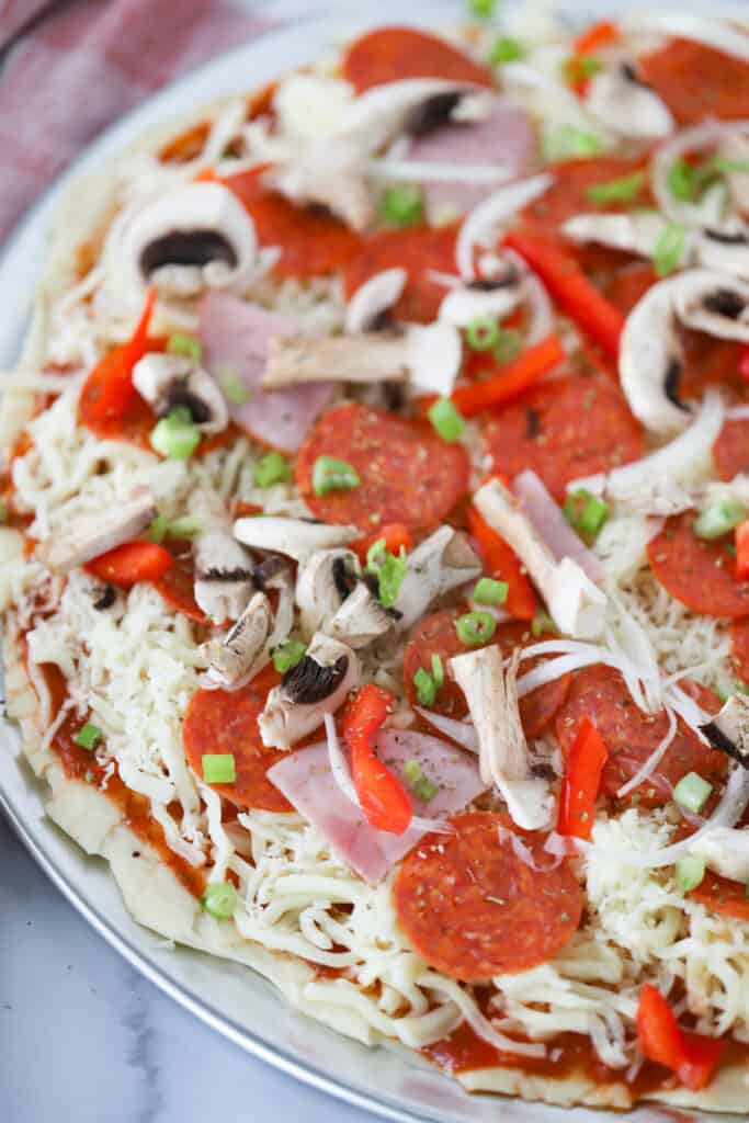 A homemade combination pizza loaded with sauce, cheese and toppings ready to bake in the oven.