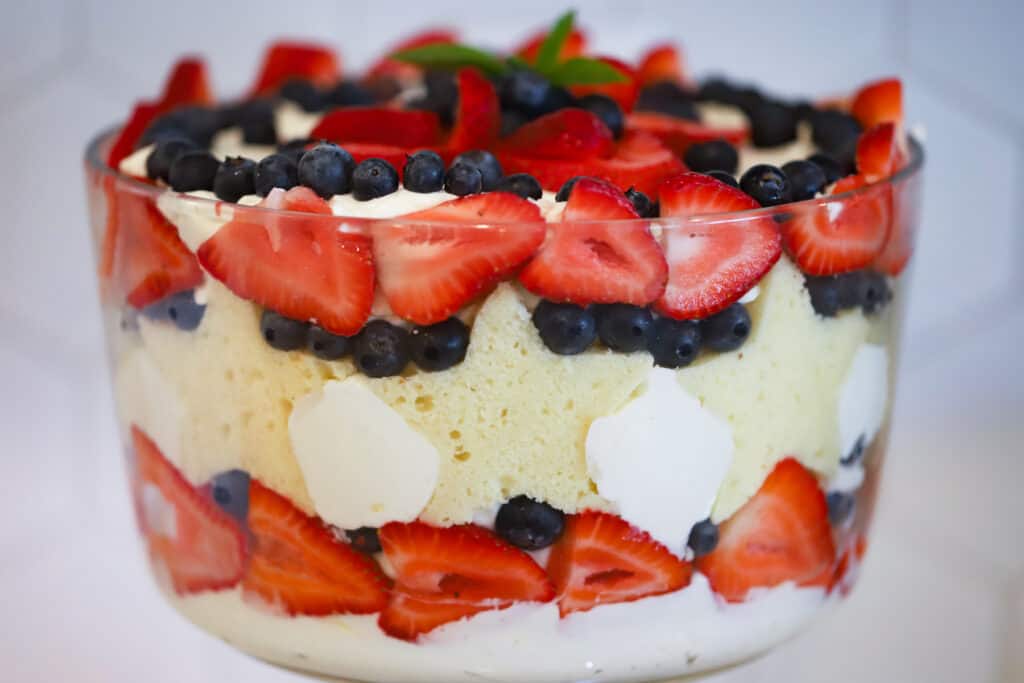The side view of a 4th of july Berry Trifle made with strawberries, blueberries, pound cake and decorated with a sprig of mint.
