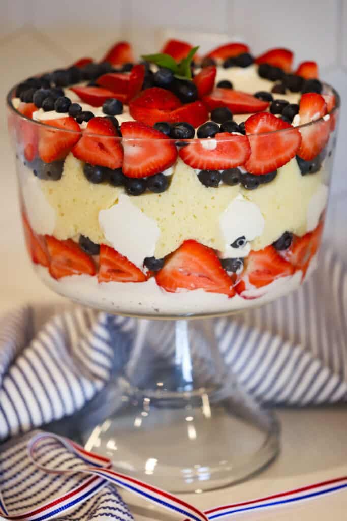 berry trifle recipe in a large trifle dish decorated with star shaped pound cake, strawberries and blueberries.