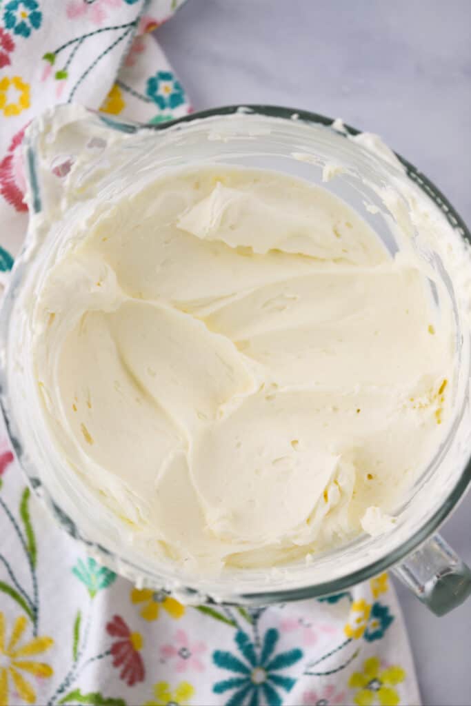 A large glass bowl filled with whipped cream and cream cheese mixture on a table.