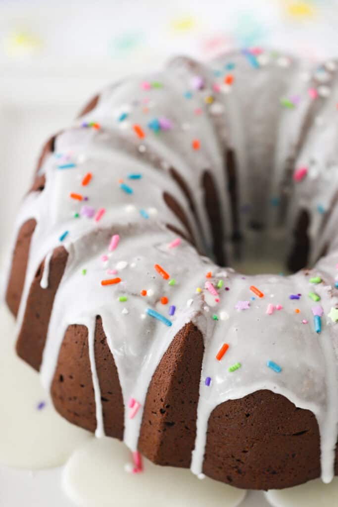 A large chocolate bundt cake topped with glaze and sprinkles.