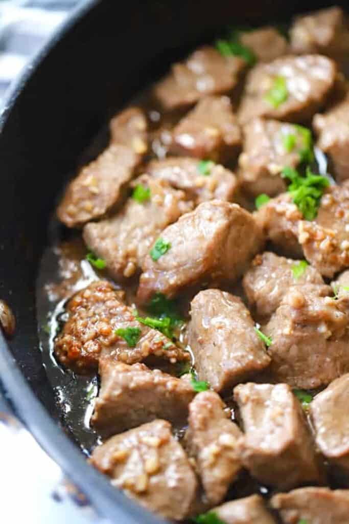 Garlic Butter Steak Bites in a cast iron skillet that are topped with parsley and ready to serve. Steak bites oven.