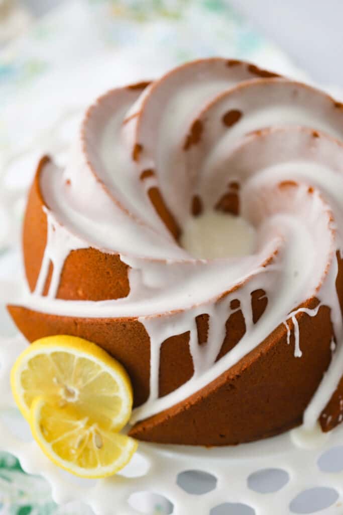 A glazed Lemonade Pound Cake recipe on a cake stand topped with glaze; lemonade pound cake.