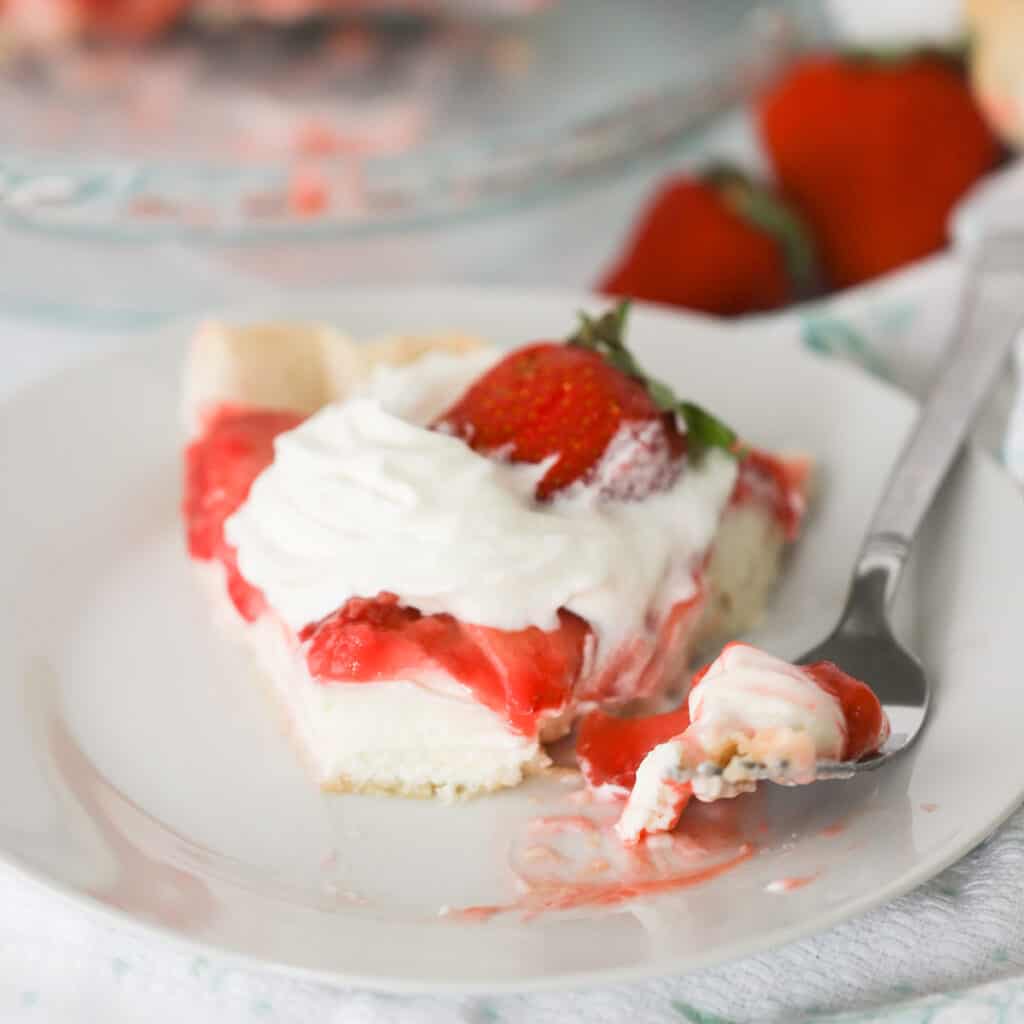 A slice of Strawberry and Cream Pie on a plate with a fork. easy easter pie recipe. 