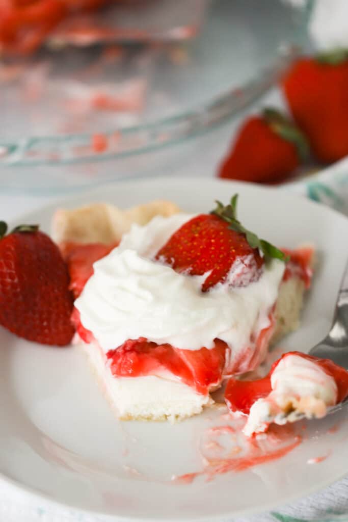Strawberry cream pie recipe, a whipped cream strawberry pie topped with fresh strawberries on a plate.