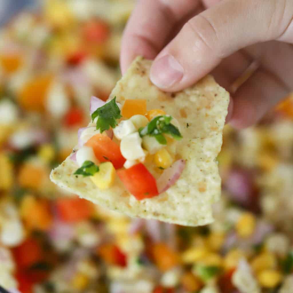 A tortilla chip with corn salsa.