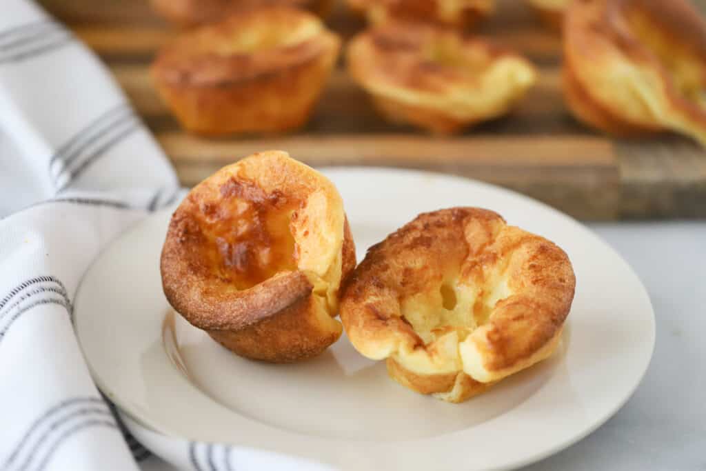 A white dinner plate with two popovers. easy popover recipe. popovers recipes. 