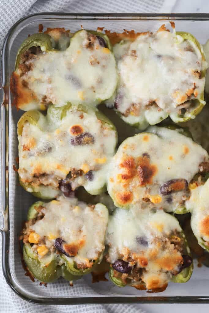 A baking dish full of Southwestern Stuffed Peppers, topped with melted cheese. stuffed peppers southwest. 