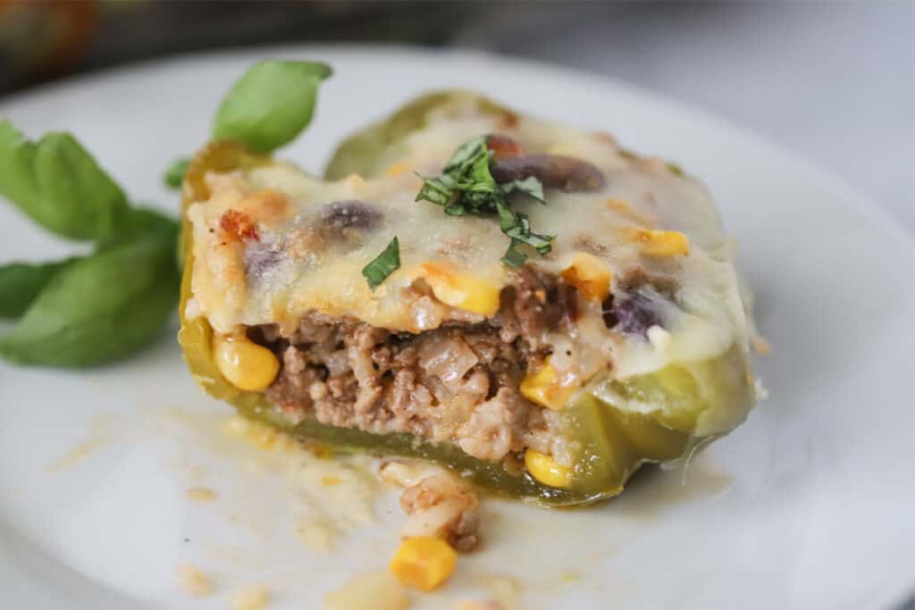 A white plate with a serving of Mexican Stuffed Bell Peppers sliced to show the filling. Southwestern stuffed peppers. 