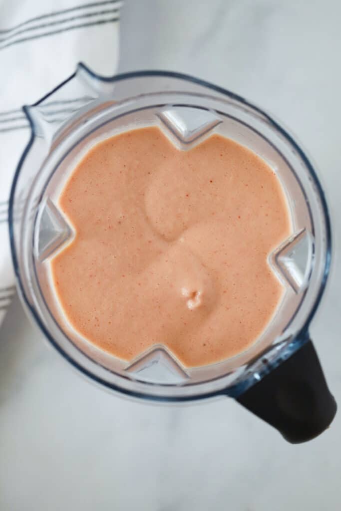 A picture from the top of the blender showing a strawberry orange juice frozen drink inside. how to make homemade strawberry orange julius recipe. original orange julius recipe. 