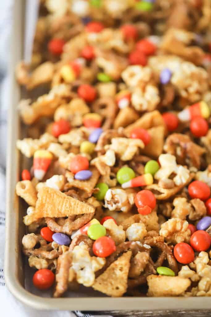 A baking tray full of Fall Party Snack mix, including Bugles, candy corn, popcorn, and M&Ms. fall snack mix.