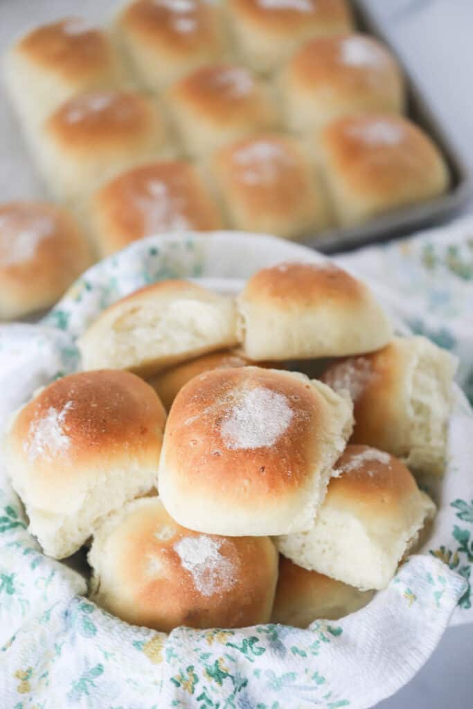 A serving basket full of Potato Rolls and lined with a decorative cloth. potato rolls recipes.