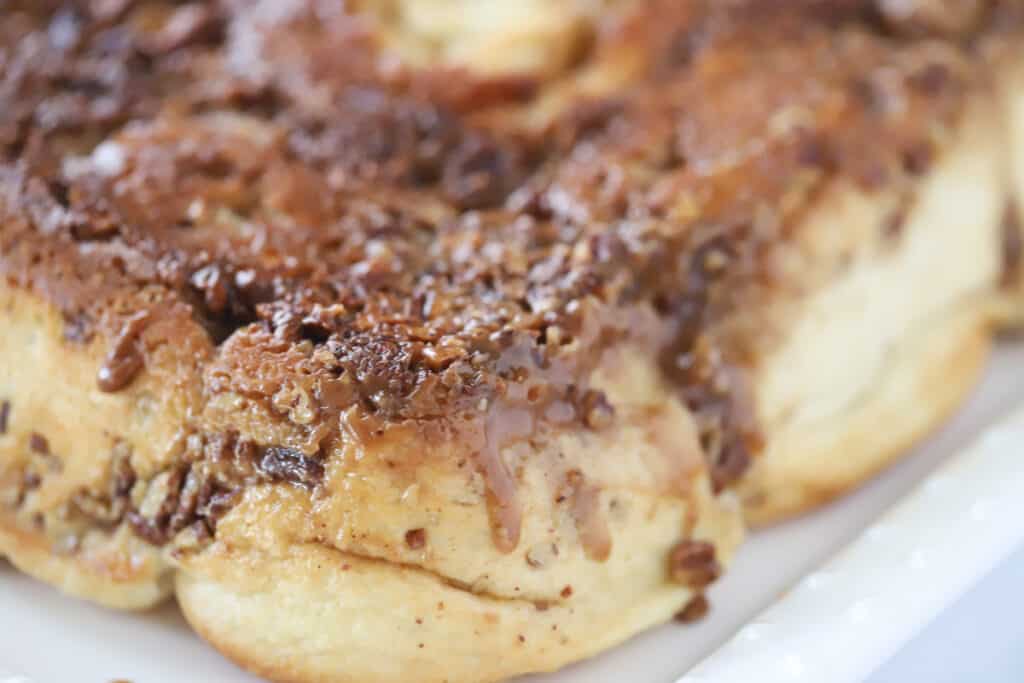 A white serving platter full of pecan sticky buns.