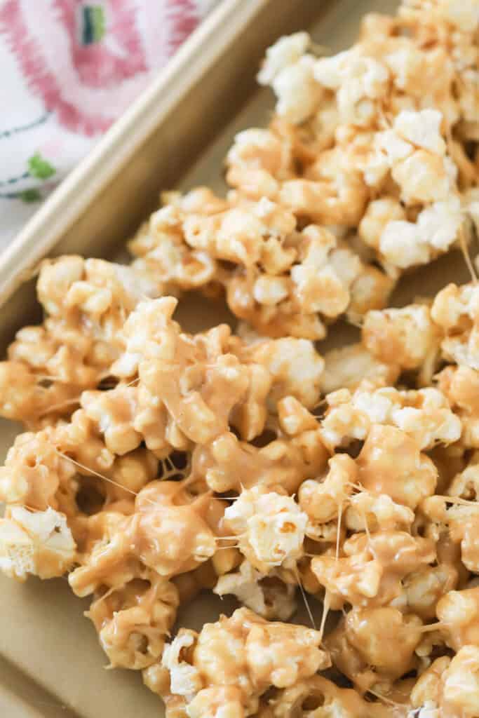 A baking sheet with a layer of Peanut Butter Popcorn cooling. popcorn peanut butter. peanutbutter popcorn, popcorn dessert, popcorn 1 cup.