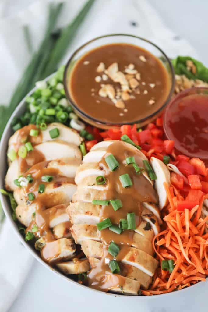 A serving bowl with Thai Chicken Chopped Salad and a ramekin of peanut sauce.
