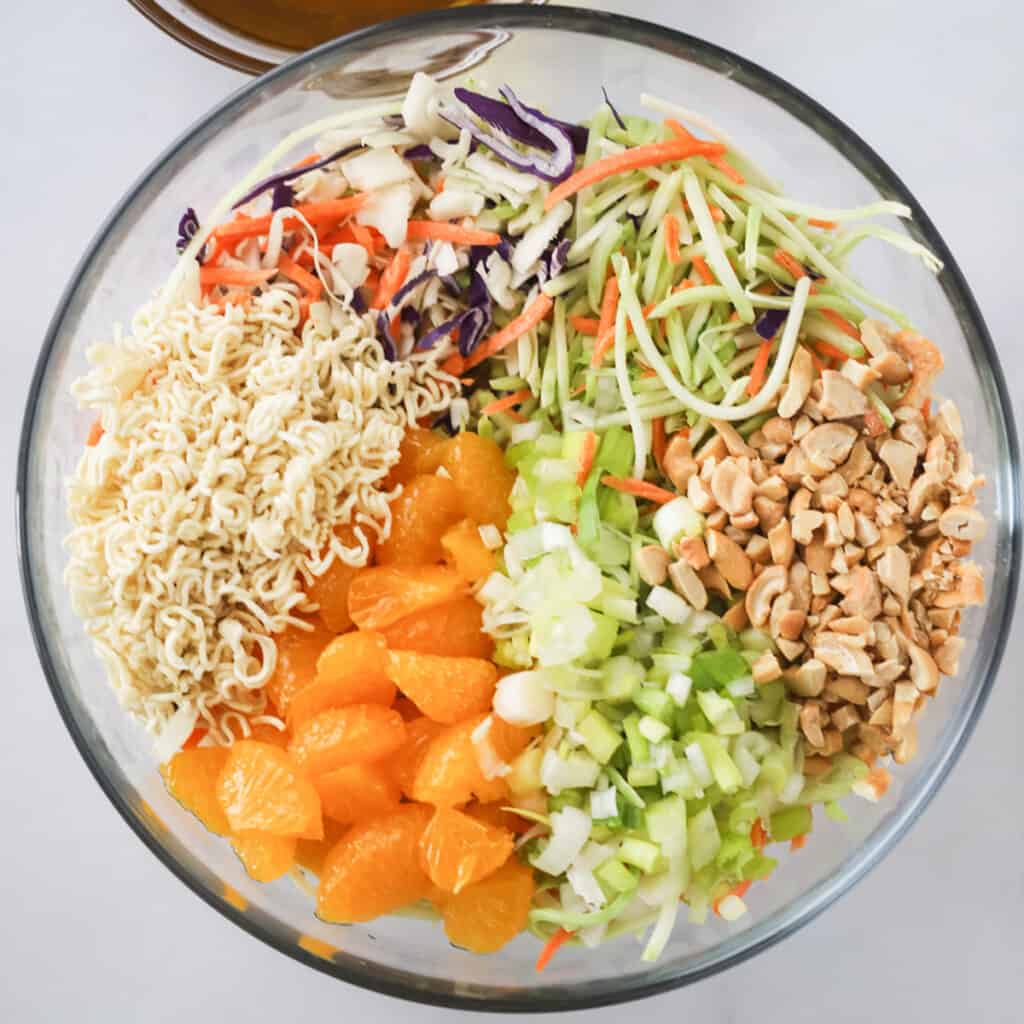 cabbage ramen salad ingredients in a large glass mixing bowl.
