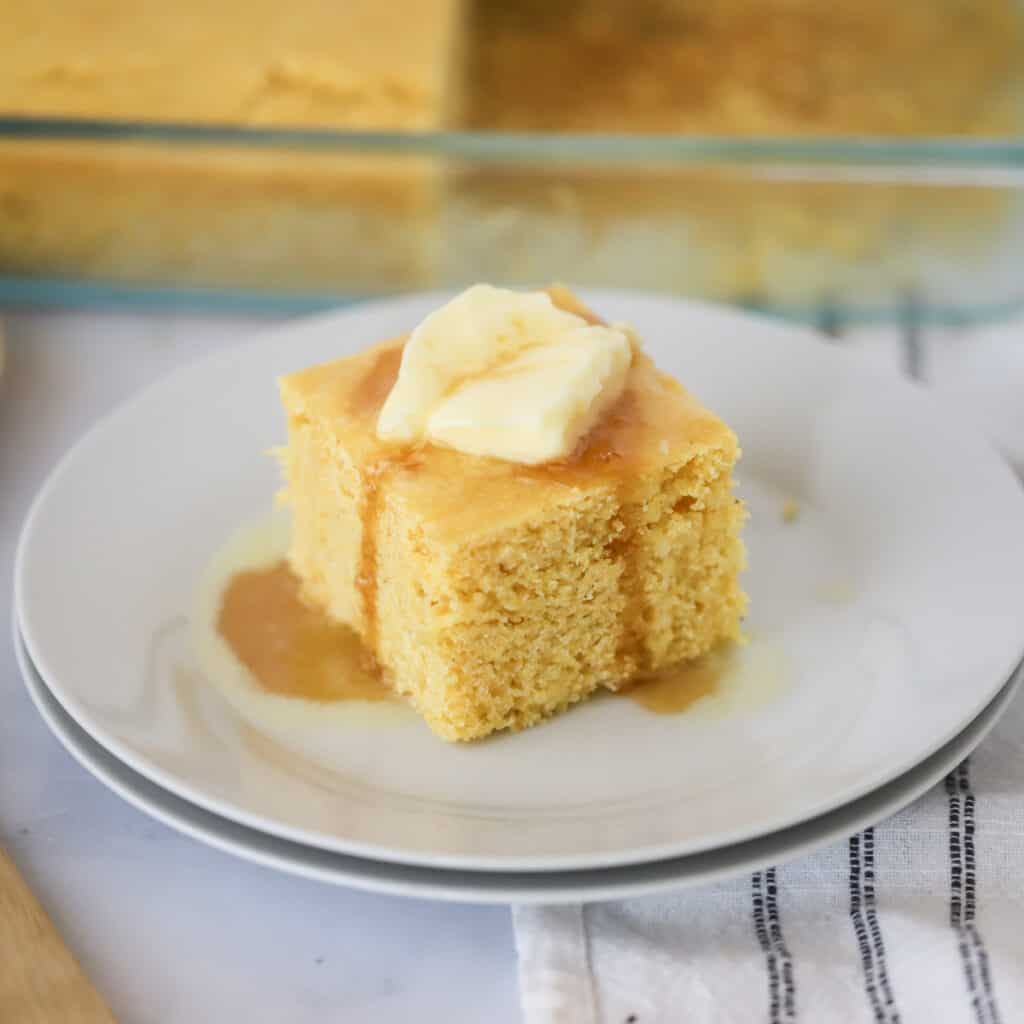 A white plate with a slice of easy homemade cornbread, this recipe will show you how to make corn bread.