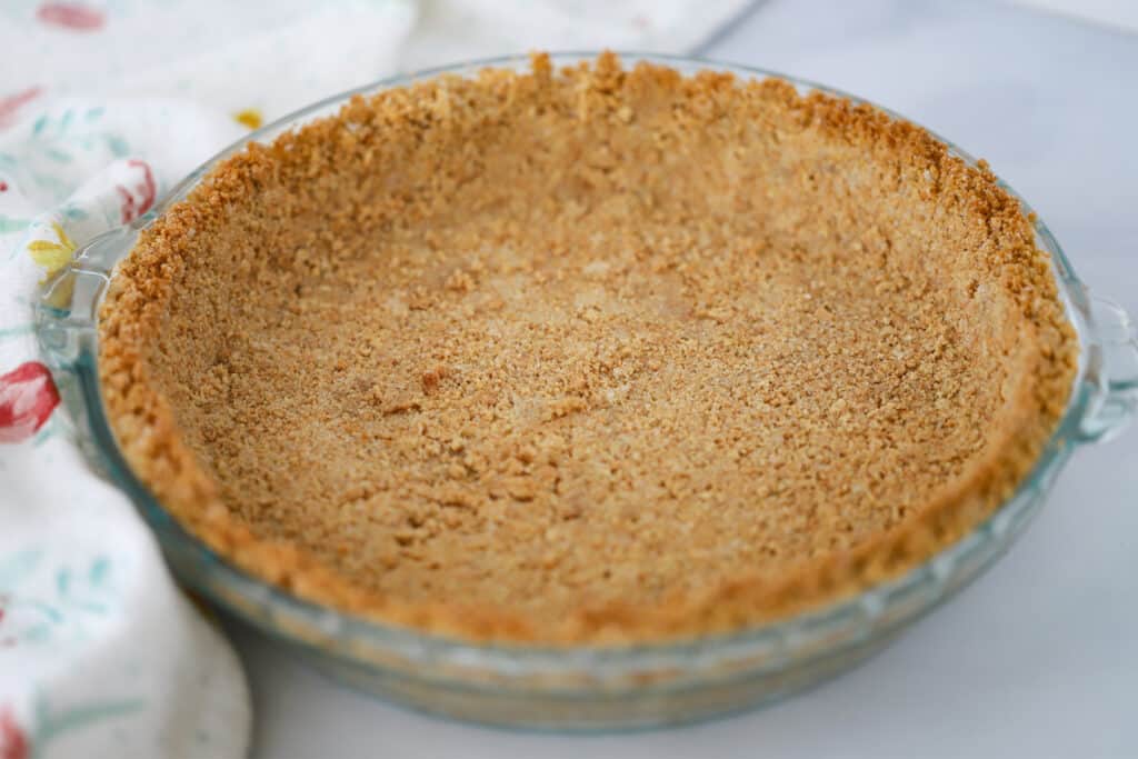A prepared graham cracker crust in a pie dish, ready to be filled with recipes for graham cracker crust pies.