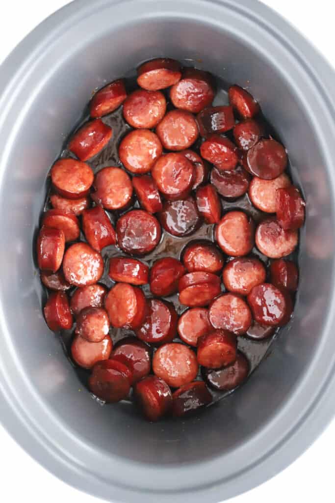 A slow cooker with sliced candied kielbasa.
