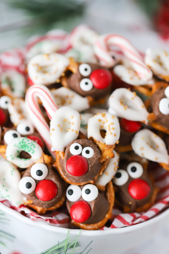 A plate full of pretzels decorated to look like reindeer.
