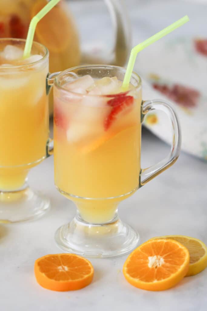 Glass mugs full of Breakfast Punch garnished with fresh orange slices and straws. brunch punch non alchoholic. 