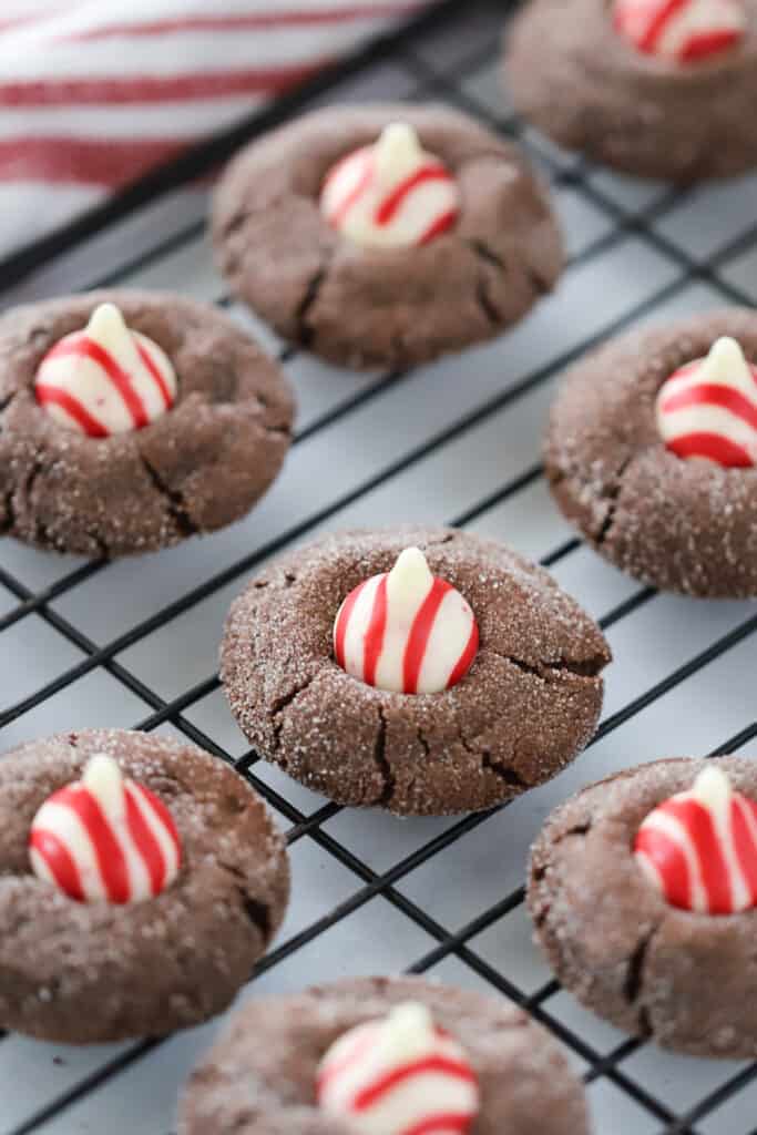 Rows of Chocolate Kiss Cookies topped with striped Hershey's Kisses on a baking rack.