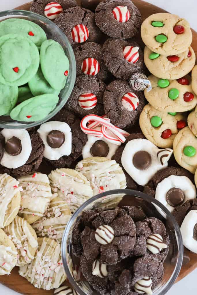 A large wooden board with different types of Christmas cookies arranged to make a cookie board.