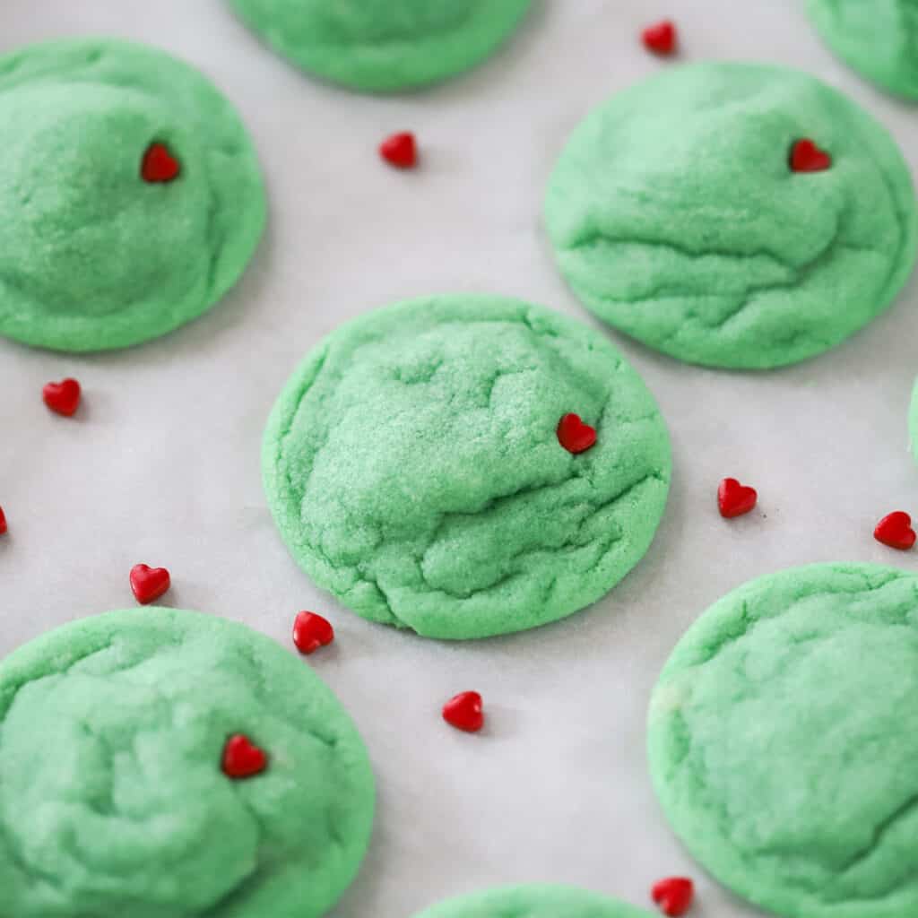 green Grinch cookies with little red candy hearts, perfect cookie platter presentation.