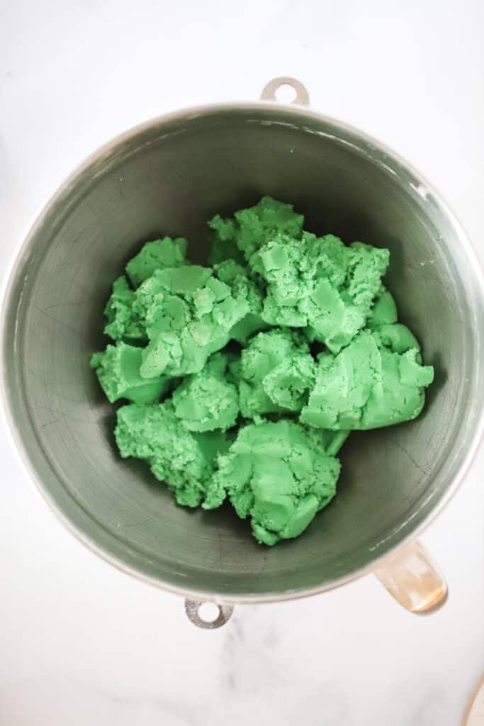 A mixing bowl full of green cookie dough.