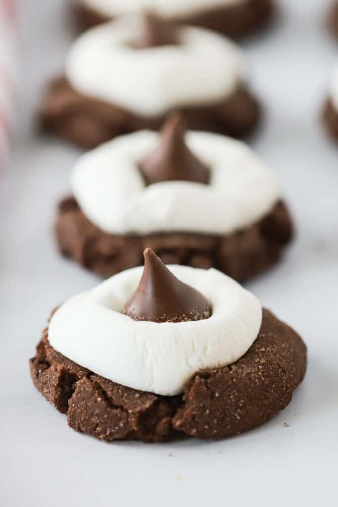 A row of Hot Chocolate Kiss Cookies topped with marshmallows and Hershey's Kisses. hot cocoa kisses, hot chocolate hershey kisses. chocolate kisses cookies. 
