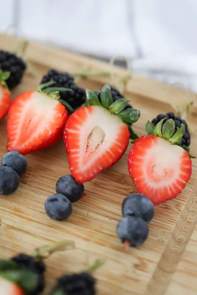 Bamboo toothpicks with fresh berries on a cutting board. Individual charcuterie cups ideas.