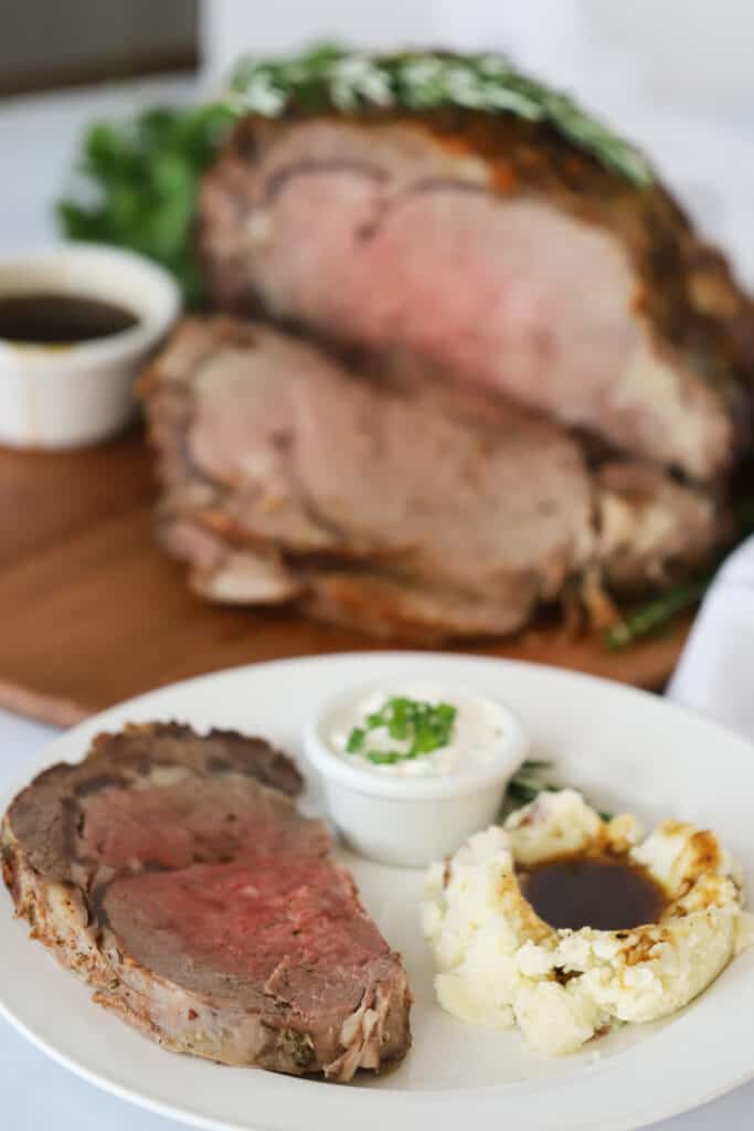 A white dinner place with Prime Rib, mashed potatoes, and a side of horseradish sauce. rib roast recipes, best prime rib recipe. 
